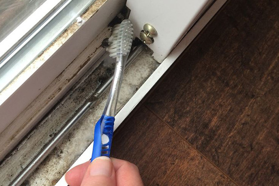 a sliding roller door track  being cleaned with a toothbrush