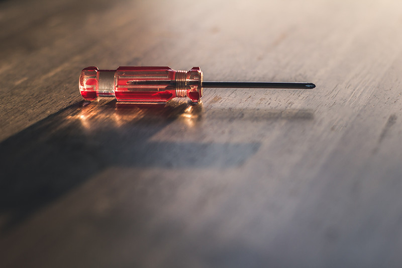 a screwdriver with a red handle on a table